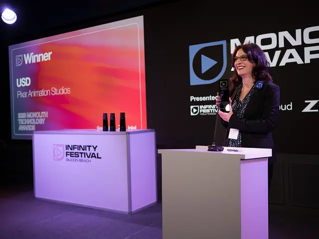 The image shows a woman standing at a podium in front of a screen, wearing a black dress and...