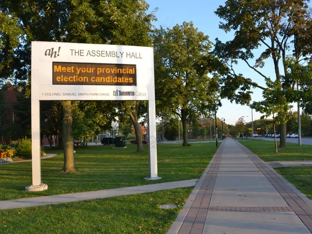 The image shows a board with text on it placed on the ground surrounded by grass, a pathway, a...