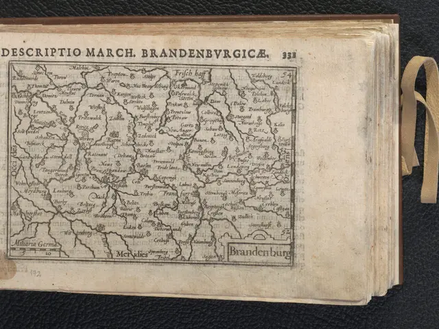 The image shows an open book with a map of Brandenburg on it, placed on a black surface. The map is...