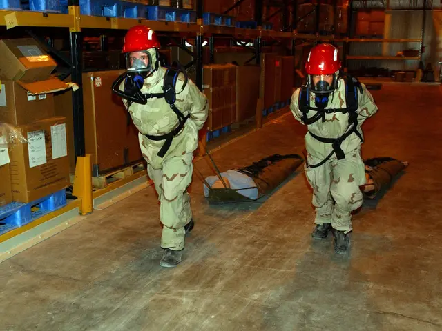The image shows two men in military uniforms and red helmets walking through a warehouse. They are...