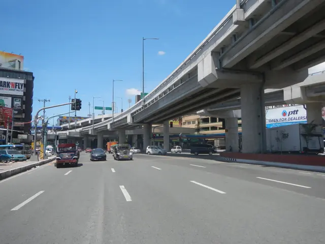 The image shows a city street filled with lots of traffic next to tall buildings, with a flyover in...