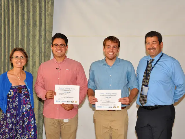 The image shows four people standing next to each other, smiling and holding certificates in their...