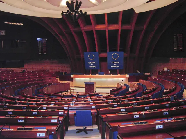 The image shows the European Parliament in Brussels, Belgium. It is a large room with tables and...