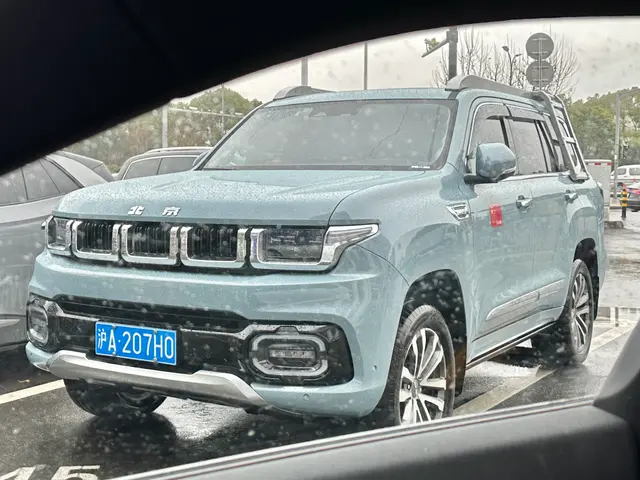 The image shows a blue Suzuki Grand Vitara parked in a parking lot next to other cars, with trees,...