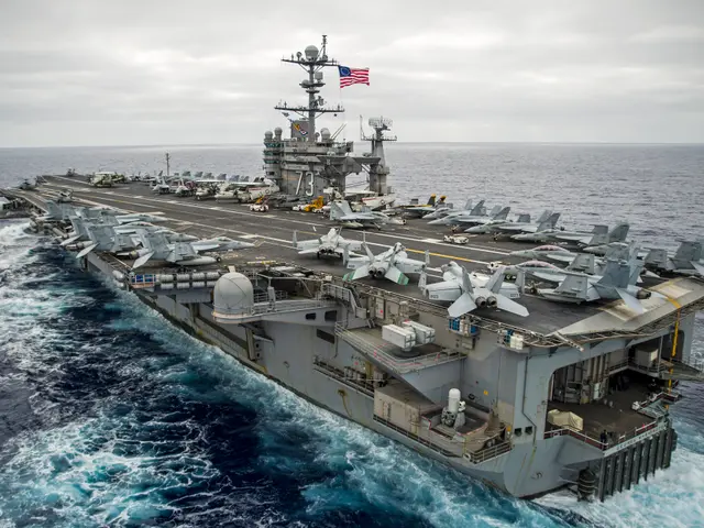 The image shows an aircraft carrier, the USS George H W Bush CVN-68, transiting the Arabian Sea. On...