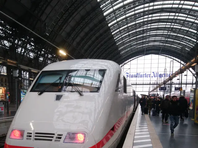 The image shows a bullet train parked at a train station with people walking on the platform. The...