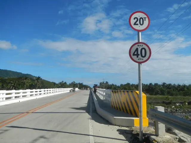 The image shows a speed limit sign on the side of a road, with a few people riding motorbikes on...