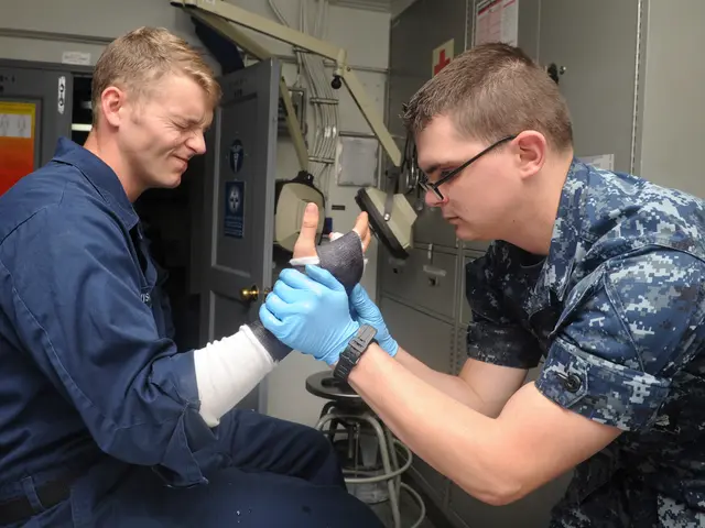 The image shows two men in military uniforms, one sitting on a chair and the other standing beside...