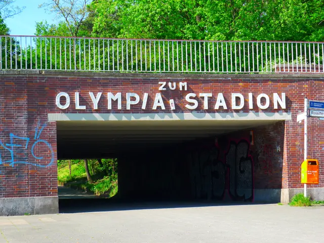 The image shows the entrance to the Olympic Stadium in Berlin, Germany. It is a bridge with text on...