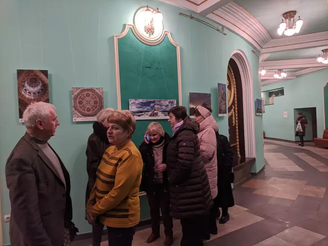 The image shows a group of people standing in a room with paintings on the walls, illuminated by...