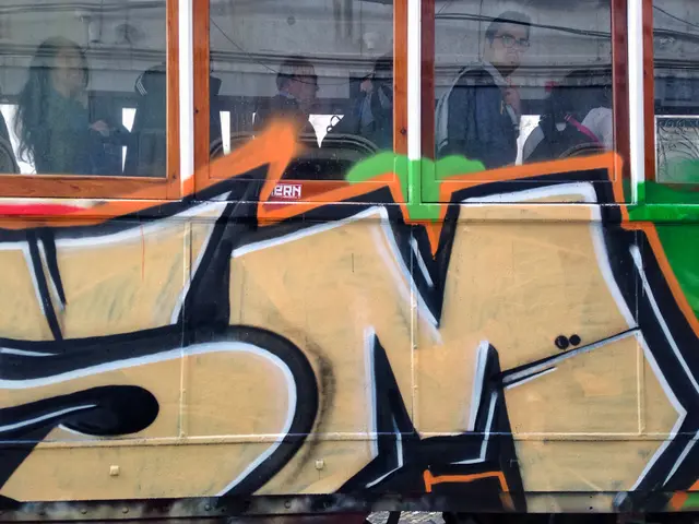 The image shows a train with graffiti on the side of it, with glass windows and people inside....