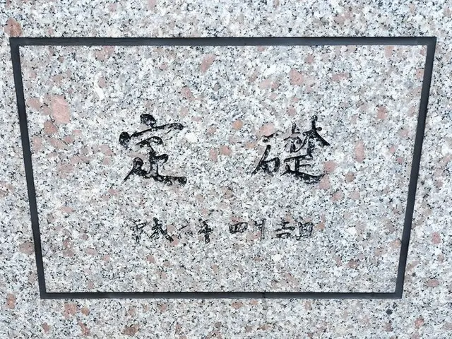 The image shows a stone wall with Chinese writing on it, which is a memorial to the victims of the...