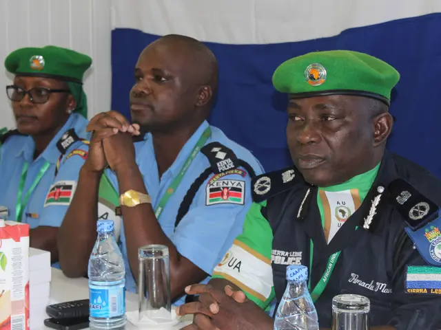 The image shows three police officers sitting at a table with water bottles, glasses, a mobile...