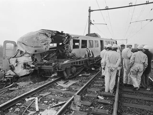 The image shows a black and white scene of a train that has crashed into a train on the tracks,...