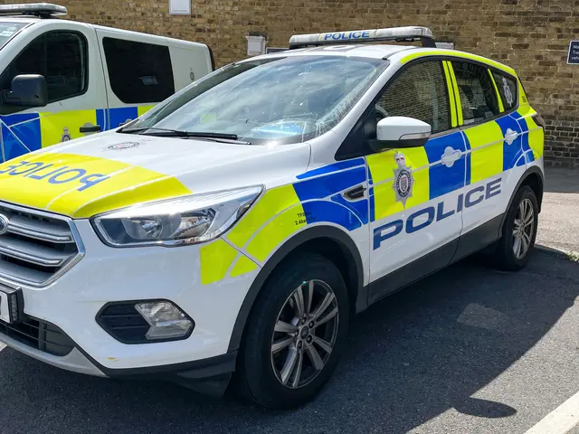The image shows two police cars parked next to each other in a parking lot, with a wall in the...
