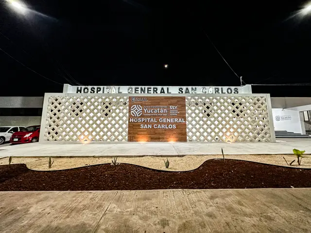 The image shows the entrance to the Hospital General San Carlos, with a name board on the wall,...