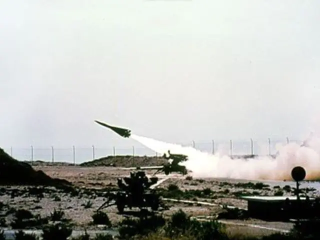 The image shows a missile being launched from a military vehicle in the desert, surrounded by...