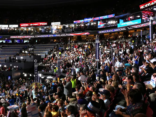 The image shows a large crowd of people standing in front of a stage at the 2016 Democratic...