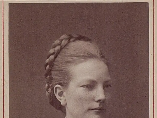 The image shows an old photo of a woman with braids in her hair. She has a gentle expression on her...