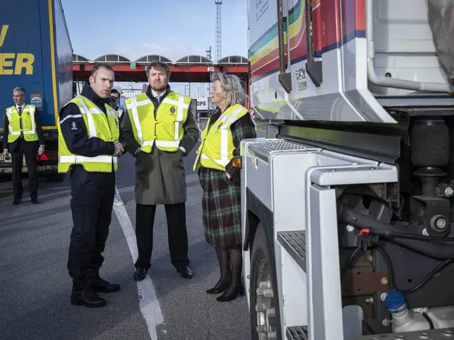The image shows a group of people standing next to a truck on a road, with a bridge in the...