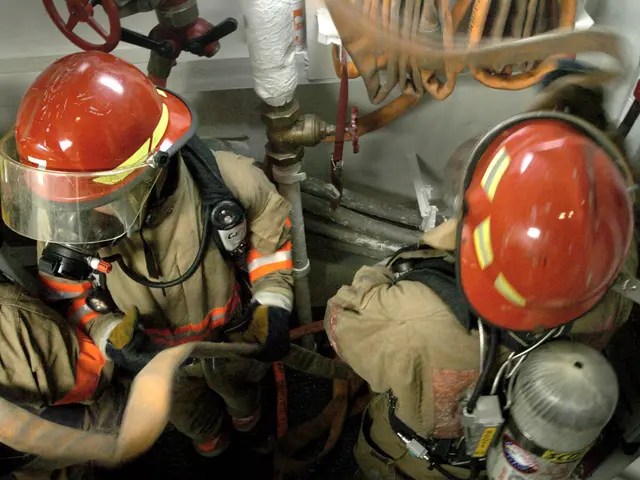 The image shows a group of firefighters wearing helmets and protective gear, working on a fire...