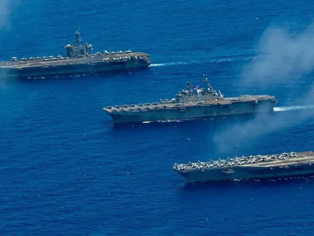 The image shows the USS George H W Bush CVN-68 transiting the Strait of Hormuz, with smoke...