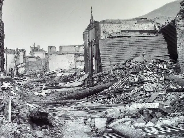The image shows a black and white photo of a destroyed building in the middle of a street,...