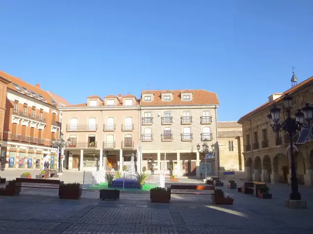 The image shows a plaza mayor in the center of a city square with a fountain in the middle of it....