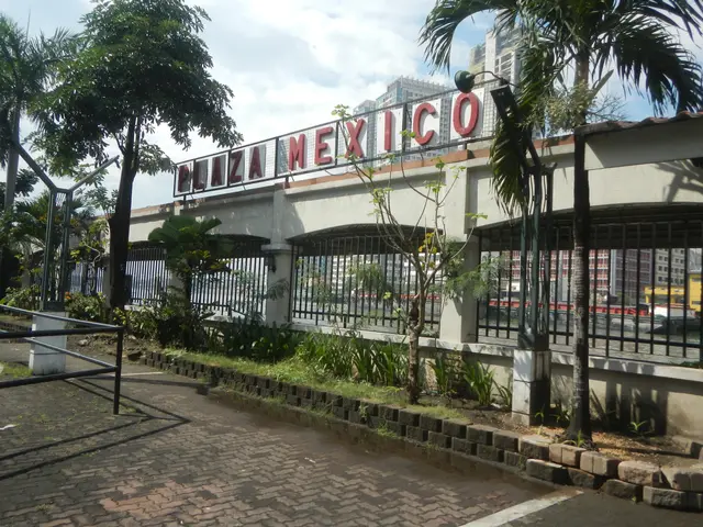 The image shows the entrance to Plaza Mexico in Mexico City, with a name board on the wall, a metal...