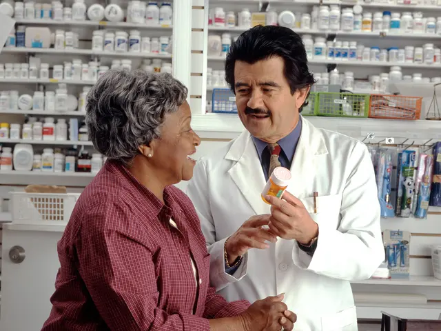 The image shows a pharmacist talking to a customer in a pharmacy. The pharmacist is wearing a white...