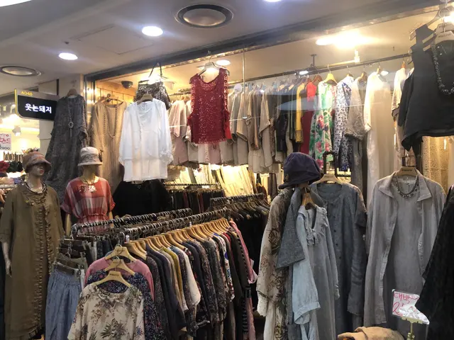 The image shows a clothing store filled with lots of clothes on display, with mannequins wearing...
