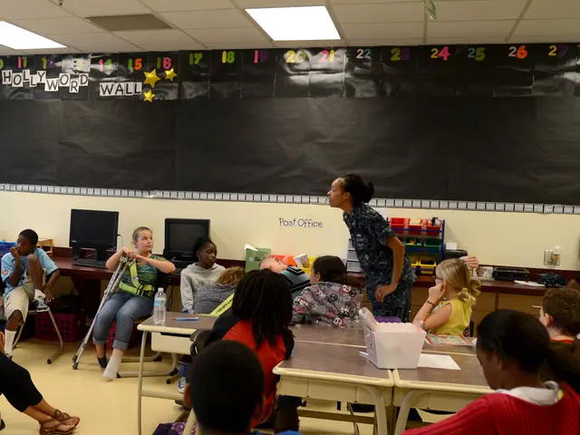 The image shows a classroom full of children sitting at desks in front of a blackboard, with a...
