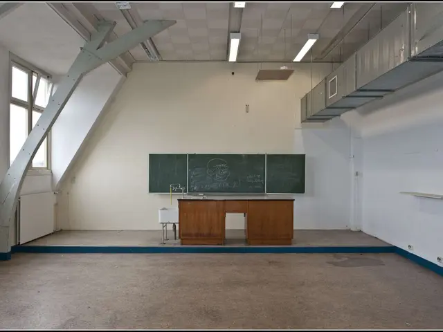 The image shows an empty classroom with a blackboard on the wall, a table, a sink with a tap, a...