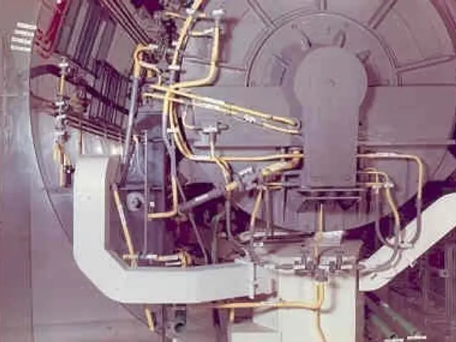 The image shows a large machine inside of a building, with a wall in the background. It appears to...