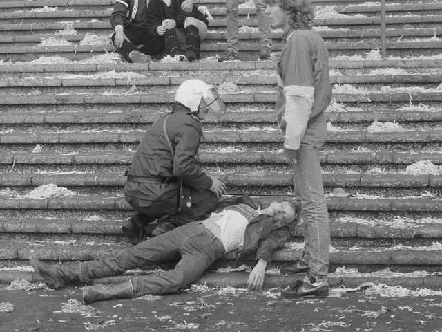 The image shows a black and white scene of a man laying on the ground next to a police officer,...