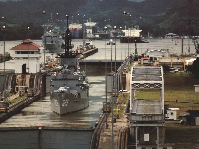 The image shows the Panama Canal in Panama City, Panama, with ships on the water, light poles,...