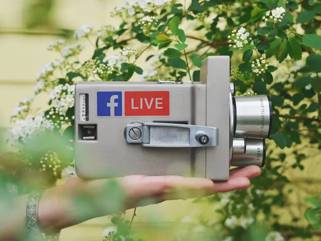 The image shows a person holding a camera with the Facebook Live logo on it, surrounded by plants...
