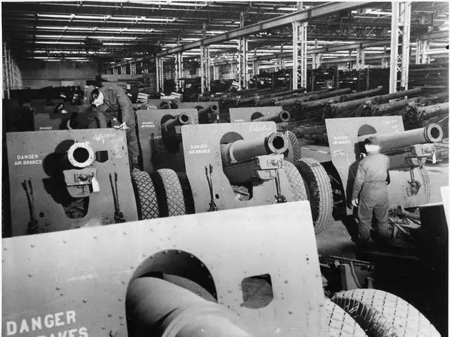 The image shows a black and white photo of men working on a large artillery gun in a factory. The...
