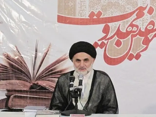 The image shows Ayatollah Ali Khamenei, the Supreme Leader of Iran, sitting on a chair in front of...