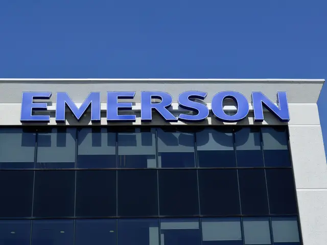 The image shows the Emerson logo on the side of a building, with a clear blue sky in the...