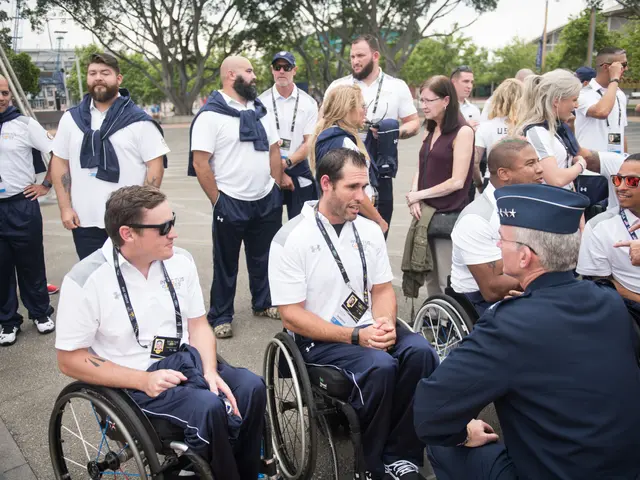 The image shows a group of people in wheelchairs talking to each other in front of a backdrop of...