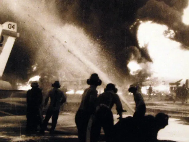 The image shows a group of people standing in front of a raging fire, with smoke billowing up into...