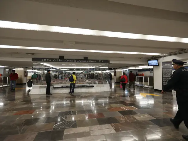 The image shows a group of people walking through a subway station, with a police officer in the...