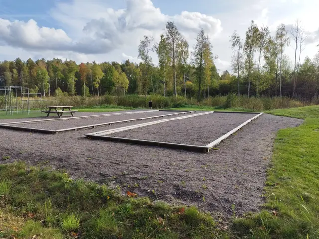 The image shows a grassy field with a picnic table in the middle of it, surrounded by trees in the...