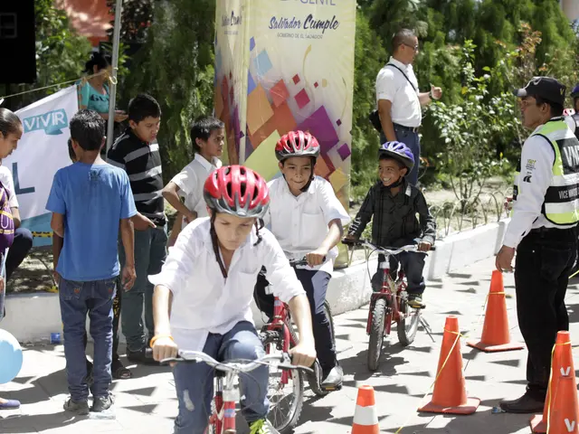 The image shows a group of children riding bicycles down a street lined with traffic cones. Some of...