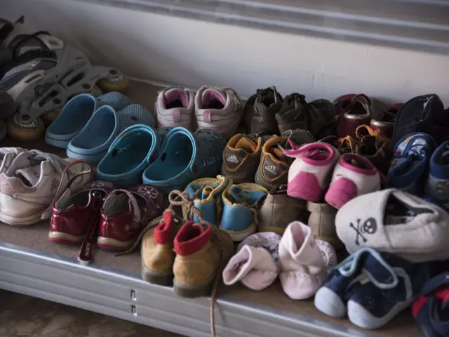 The image shows a shelf filled with lots of different types of shoes, with a wall in the...
