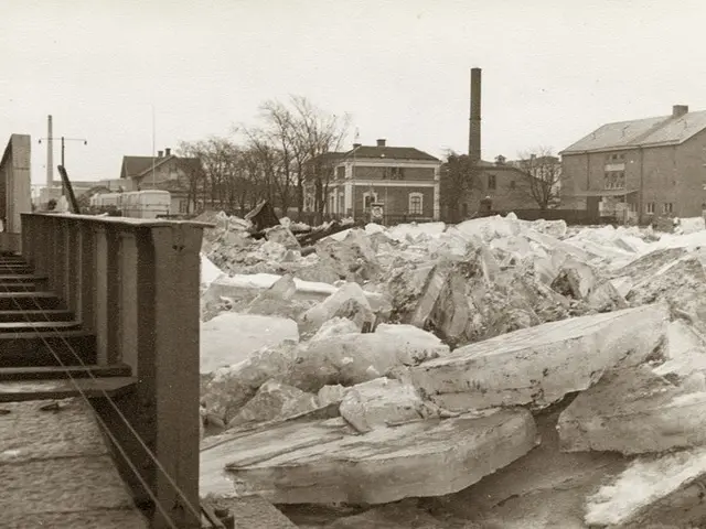 The image shows a black and white photo of a large pile of ice on the side of a road, with stairs...