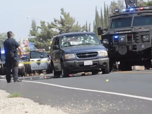 The image shows a police car parked on the side of the road next to a police truck, with a group of...