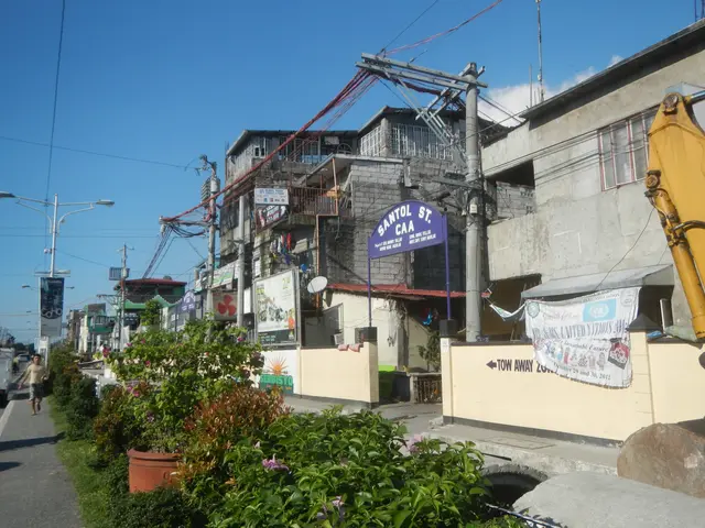 The image shows a city street with buildings, street poles, street lights, electric poles, electric...