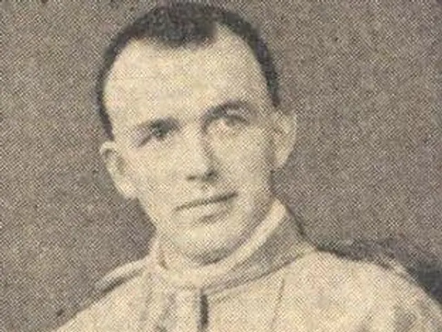 The image shows a black and white photo of a man in a priest's robes, believed to be the first...